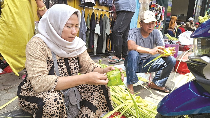 BERNILAI EKONOMI: Nadia, istri Agus Maksum, membuat selongsong ketupat di Jalan Panglima Sudirman, Bangkalan, Sabtu (5/4). (IMAMUDIN/JPRM)