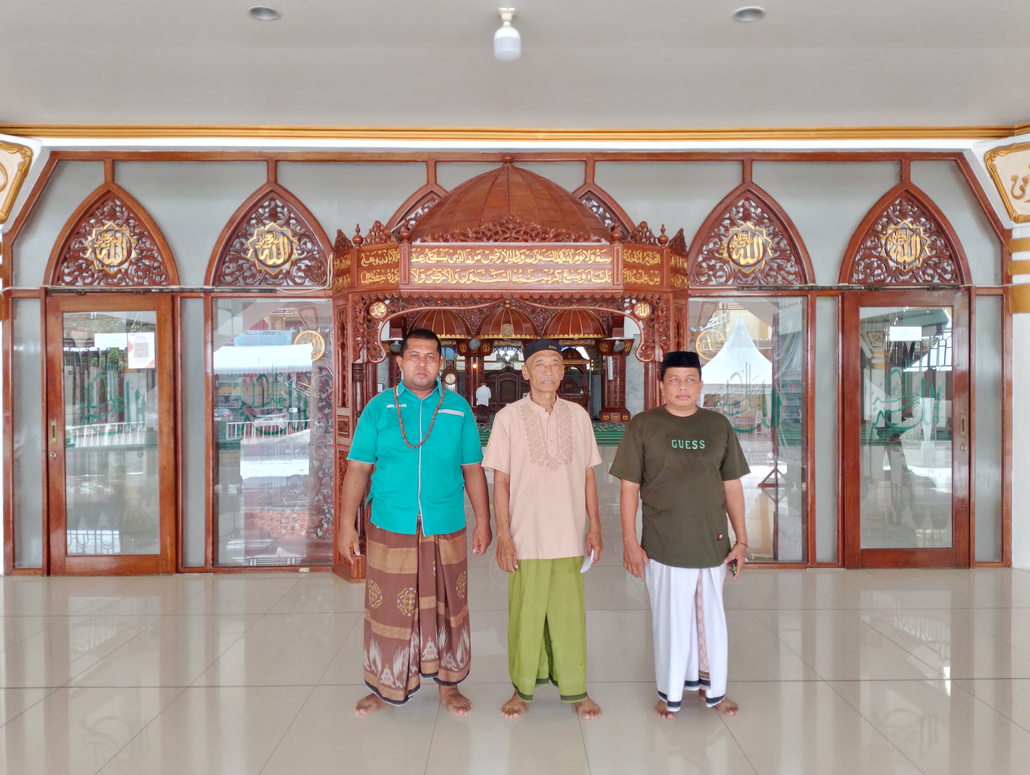 TAKMIR: Moh. Roziq, pengurus Masjid Agung Asy-Syahied Sampang (kiri), bersama dua warga berfoto bersama di depan pintu masuk masjid, Jumat (28/3). (UBAIDILLAHIR RA&rsquo;IE/JPRM)