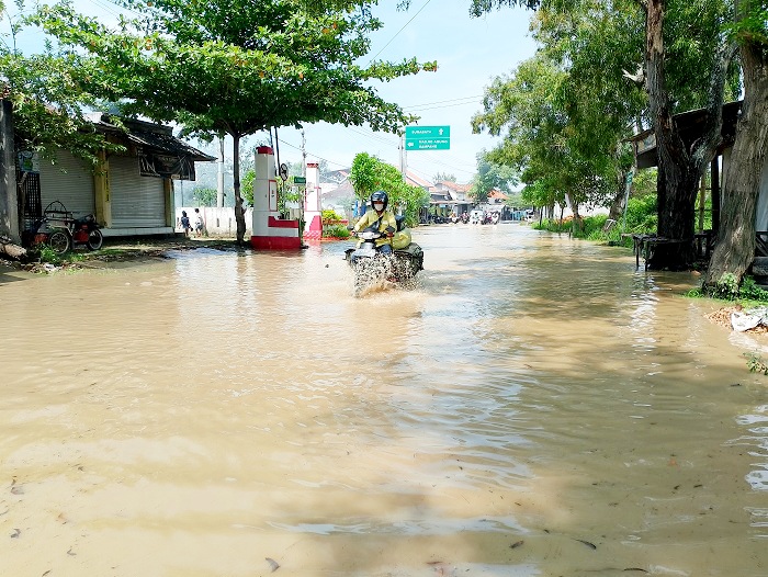 DERAS: Warga menerobos luapan banjir Kali Kemuning di Jalan Raya Imam Bonjol, Kelurahan Dalpenang, Kecamatan Kota Sampang, Jumat (7/3). (UBAIDILLAHIR RAIE/JPRM)