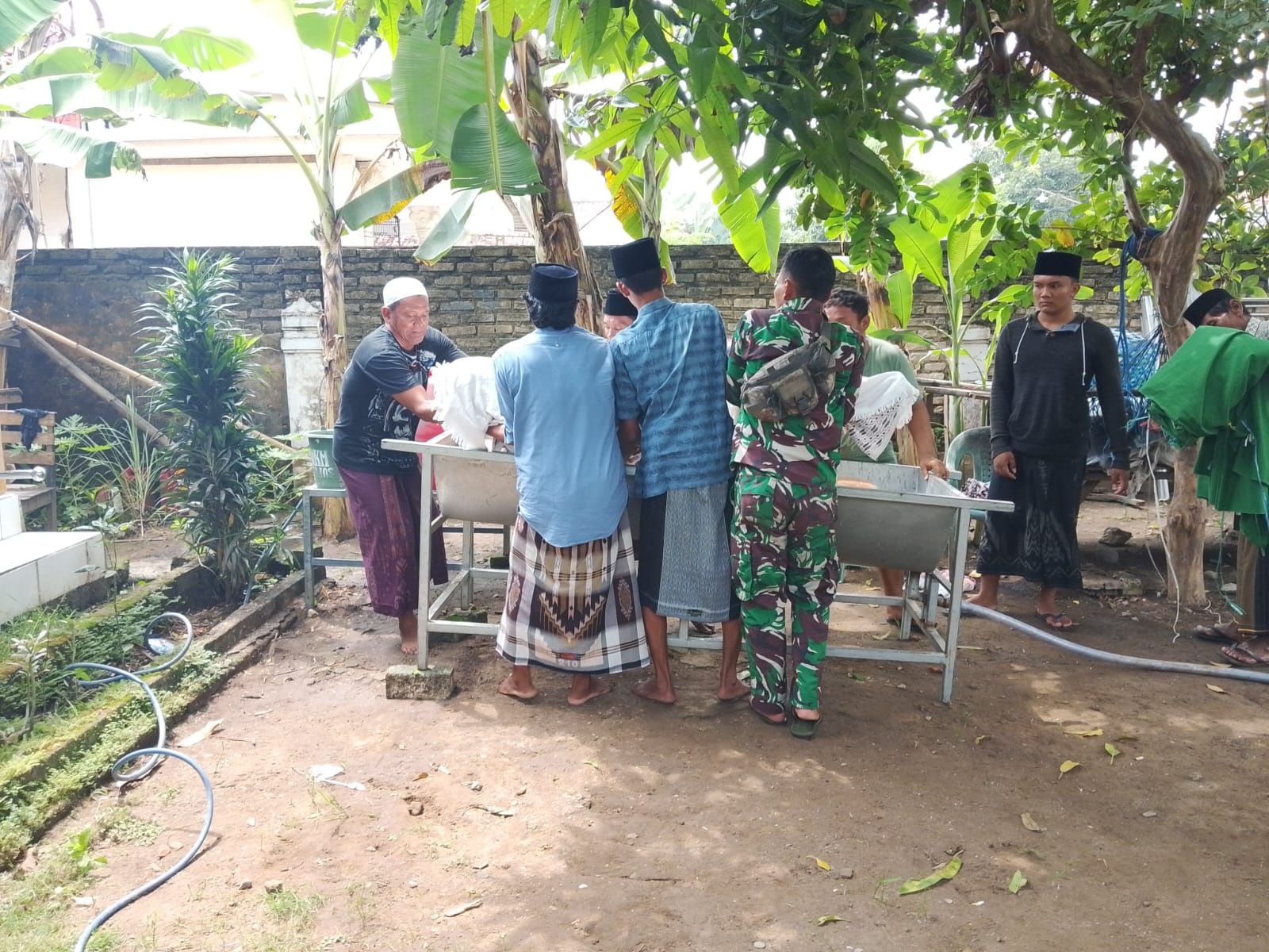 RUMAH DUKA: Warga Desa Martajasah sedang memandikan jenazah Samiun di rumah duka Kamis (10/4). (SATPOLAIRUD POLRES BANGKALAN UNTUK JPRM)