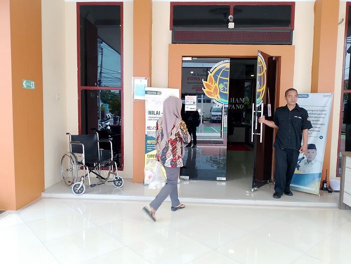 SIGAP: Petugas&nbsp;keamanan sedang membukakan pintu saat ada warga yang hendak memasuki kantor BPN Sampang, Kamis (18/4). (UBAIDILLAHIR RA&rsquo;IE/JPRM)
