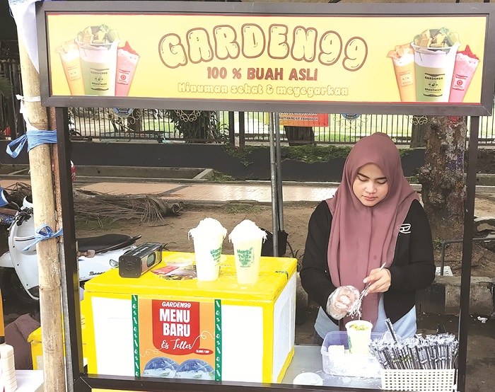 MENGUNTUNGKAN: Uswatun Hasanah tengah meracik minuman di stand booth-nya, Jumat (28/3). (HOLILURROHMAN UNTUK JPRM)