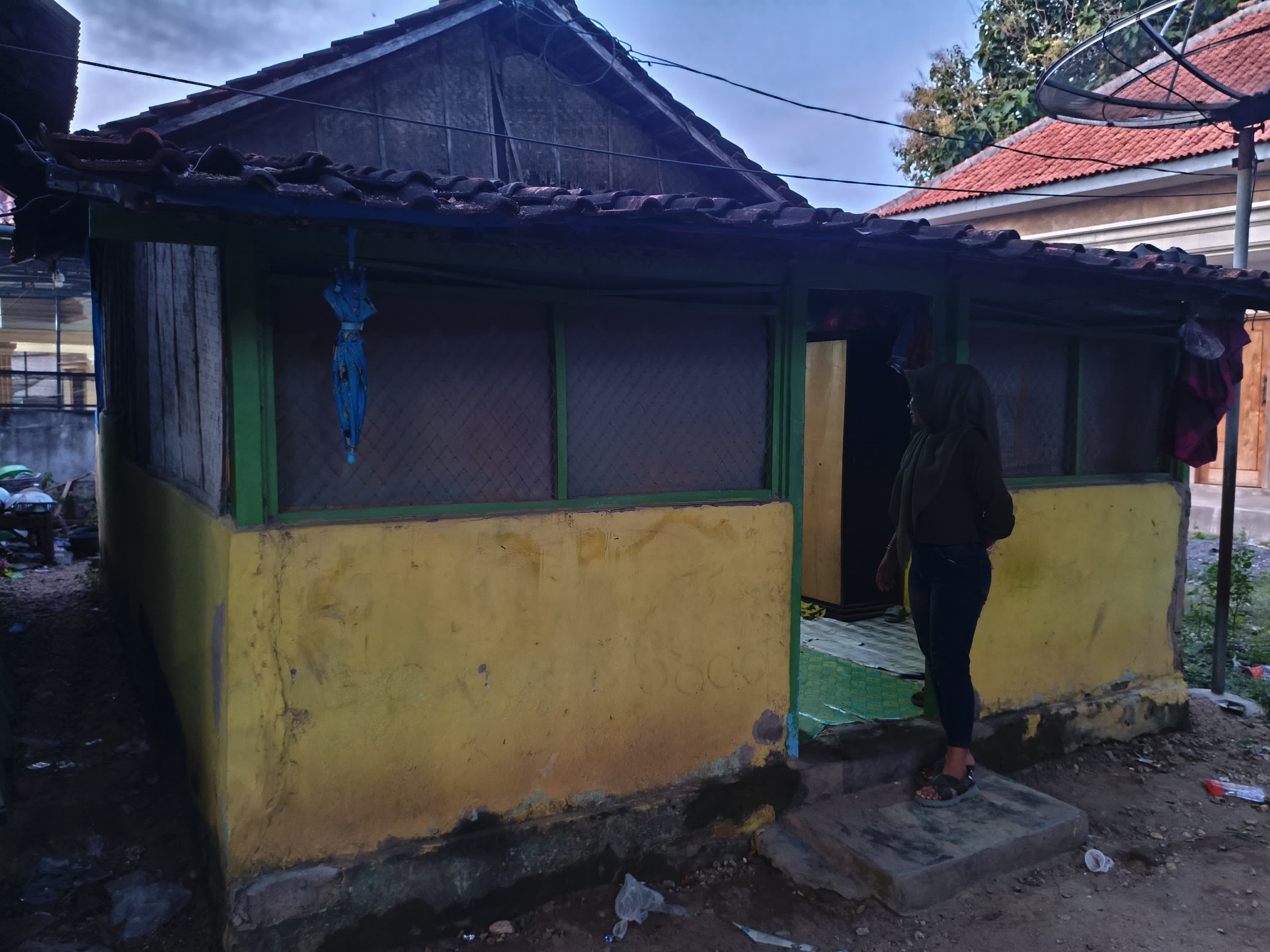 TIDAK MAMPU: Seorang perempuan keluar dari rumah tidak layak huni di Desa Tlontoraja, Kecamatan Pasean, Pamekasan, (Senin (28/4)). (S BASIER UNTUK JPRM)