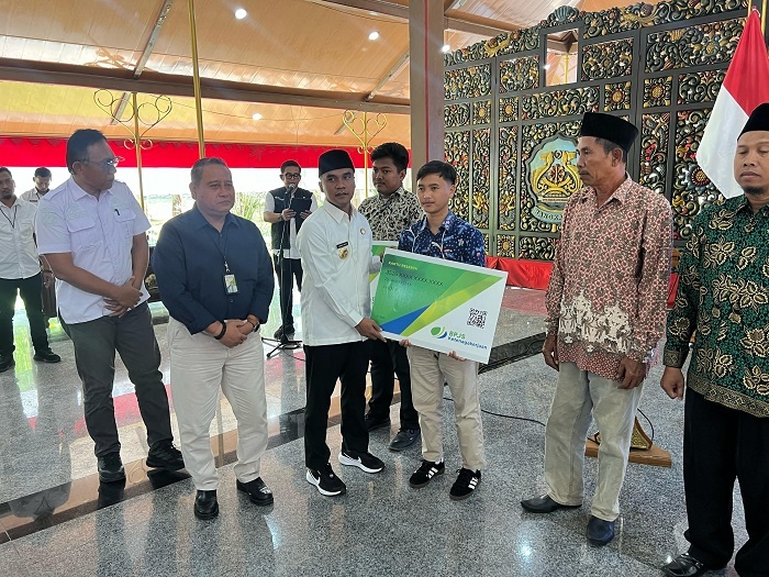 TERLINDUNGI: Bupati Bangkalan Lukman Hakim didampingi Kepala BPJamsostek Cabang Madura Indriyatno saat penyerahan kartu kepersertaan di Pendopo Agung, Rabu (30/4). (IMAMUDIN/JPRM)