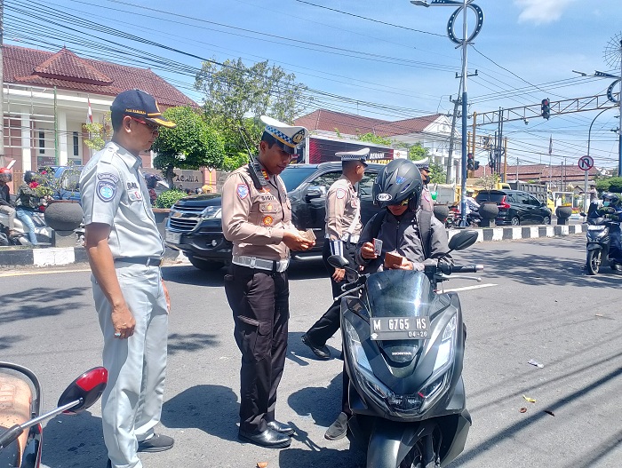 RAZIA: Kasatlantas Polres Sampang AKP Sigit Ekan Sahudi mengecek dokumen kendaraan pengendara saat melakukan razia di Jalan Jaksa Agung Suprapto kemarin. (UBAIDILLAHIR RA&rsquo;IE/JPRM)