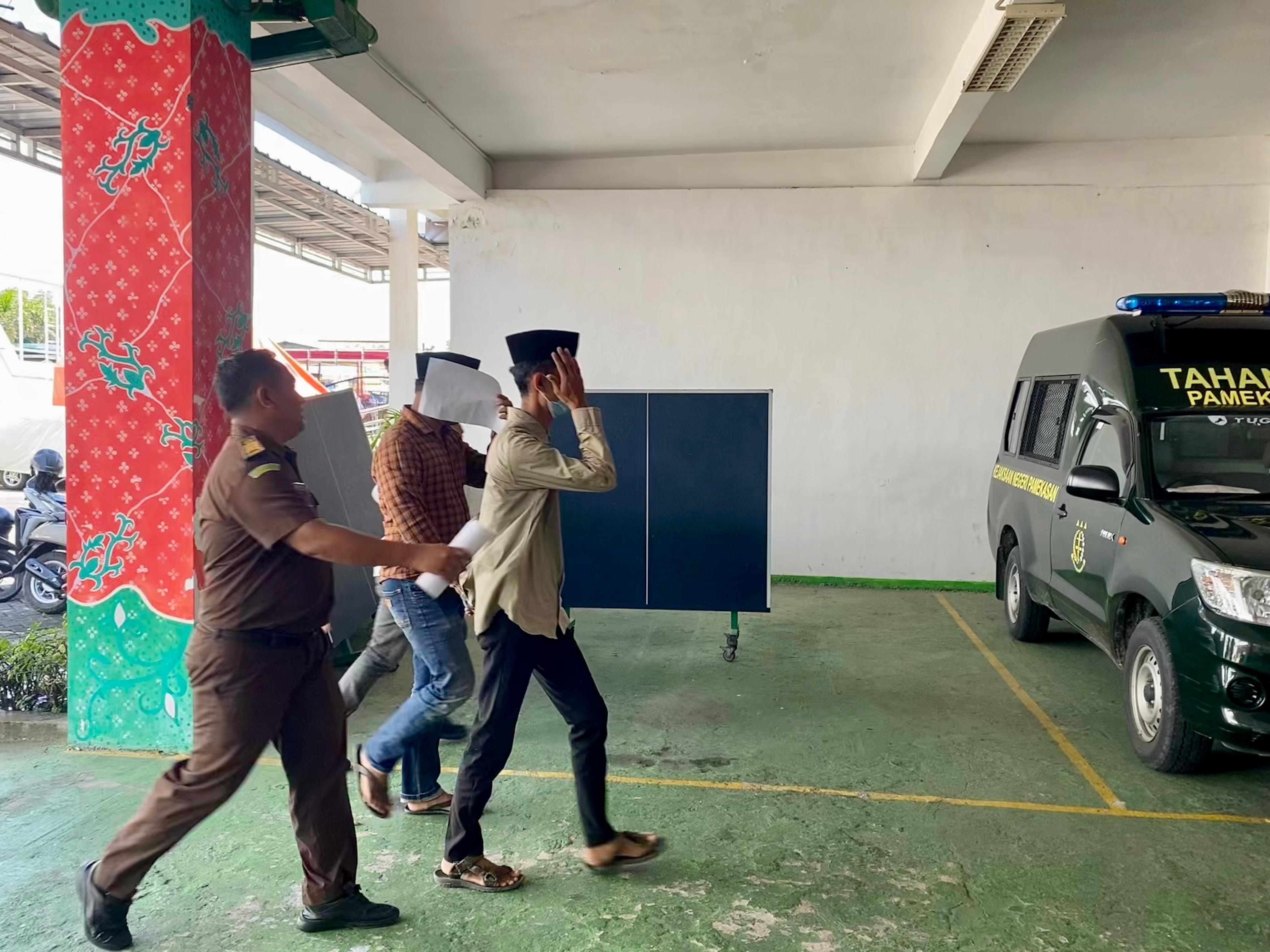 TUTUP MUKA: Tersangka kasus dugaan pemalsuan surat digiring ke mobil tahanan Kejari Pamekasan, Rabu (30/4). (MOH. IQBAL AFGANI/JPRM)