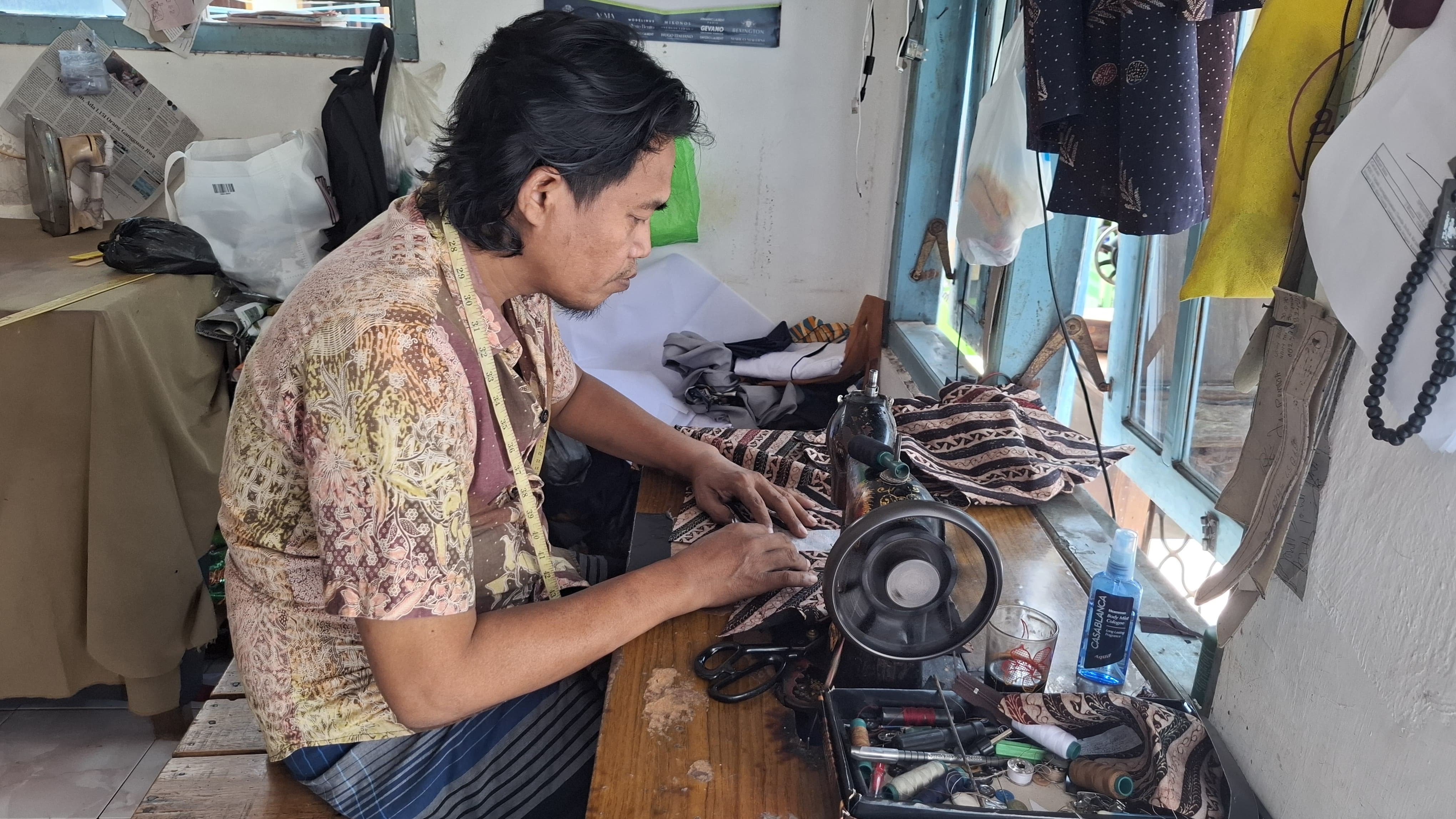 PELAKU IKM: Syaifiudin menjahit baju pesanan pelanggan di Kelurahan Kemayoran, Kecamatan Kota Bangkalan, kemarin (1/5). (IMAMUIDN/JPRM)