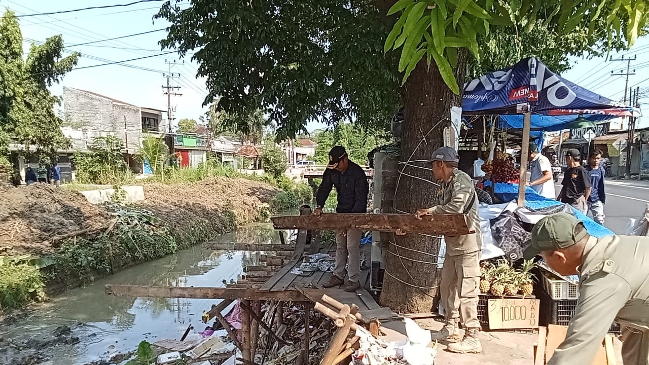 HARUS TERTIP: Personel Satpol PP Bangkalan membongkar lapak PKL di tepi DAS Tunjung, Kecamatan Burneh, kemarin. (SATPOL PP UNTUK JPRM)