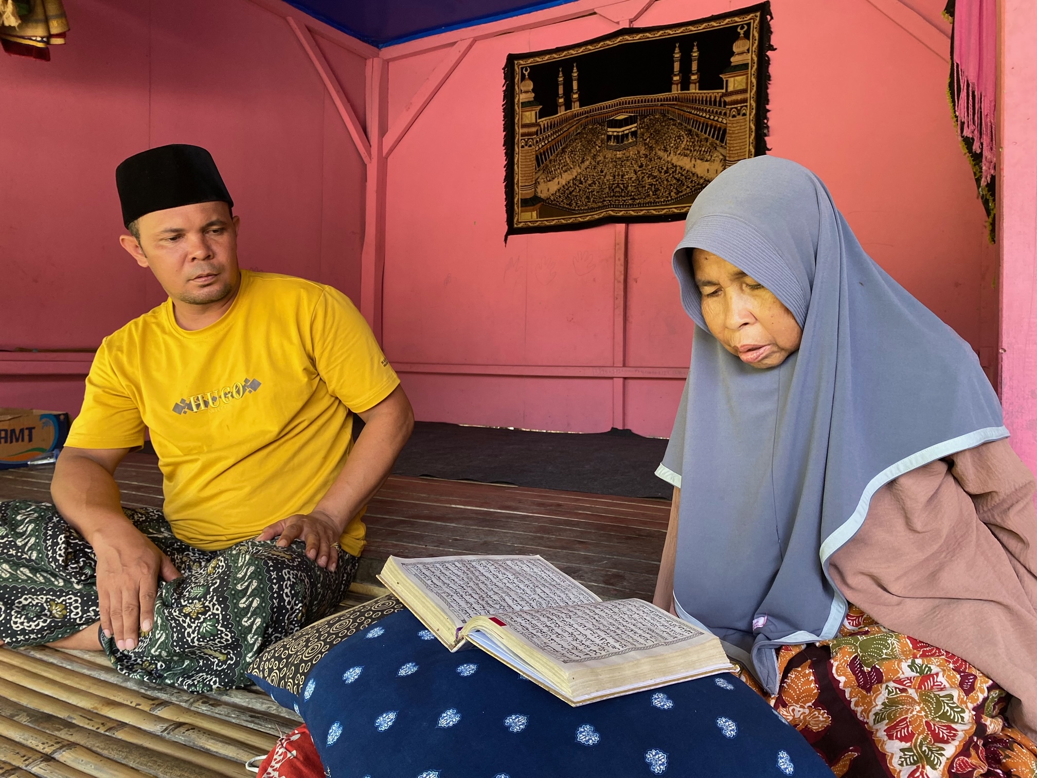 TEGAR: Marhamah didampingi menantunya, Sahrul Gunawan (kaus kuning), membaca Al-Qur&rsquo;an di langgar di Desa Palengaan Laok, Kecamatan Pelangaan, Pamekasan, Senin (5/5). (AYU LATIFAH/JPRM)