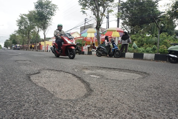 BUTUH PERBAIKAN: Pengendara melintas di sekitar jalan berlubang di Jalan Soekarno- Hattta Bangkalan, Jumat (10/5). (VIVIN AGUSTIN HARTONO/JPRM)