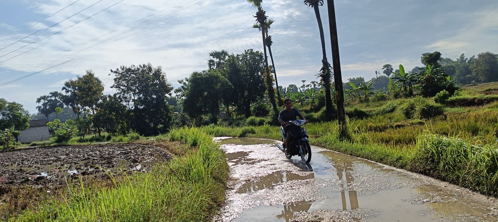 GENANGAN: Pengendara motor melintas di jalan rusak penghubung Kecamatan Gapura dan Kalianget di Desa Gapura Barat, yang tergenang air, Minggu (11/5).