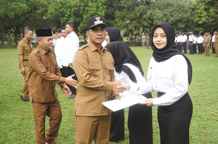 PELAYAN MASYARAKAT: Bupati Bangkalan Lukman Hakim didampingi wakilnya, Moch. Fauzan Ja&rsquo;far, menyerahkan SK pengangkatan CPNS setelah apel di halaman kantor pemkab Senin (26/5). (PROKOPIM UNTUK JPRM)