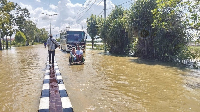 BUTUH PENANGANAN: Warga melintas di jalan nasional Sumenep&mdash;Pamekasan yang terendam banjir, Rabu (14/5). (MOH. LATIF/JPRM)
