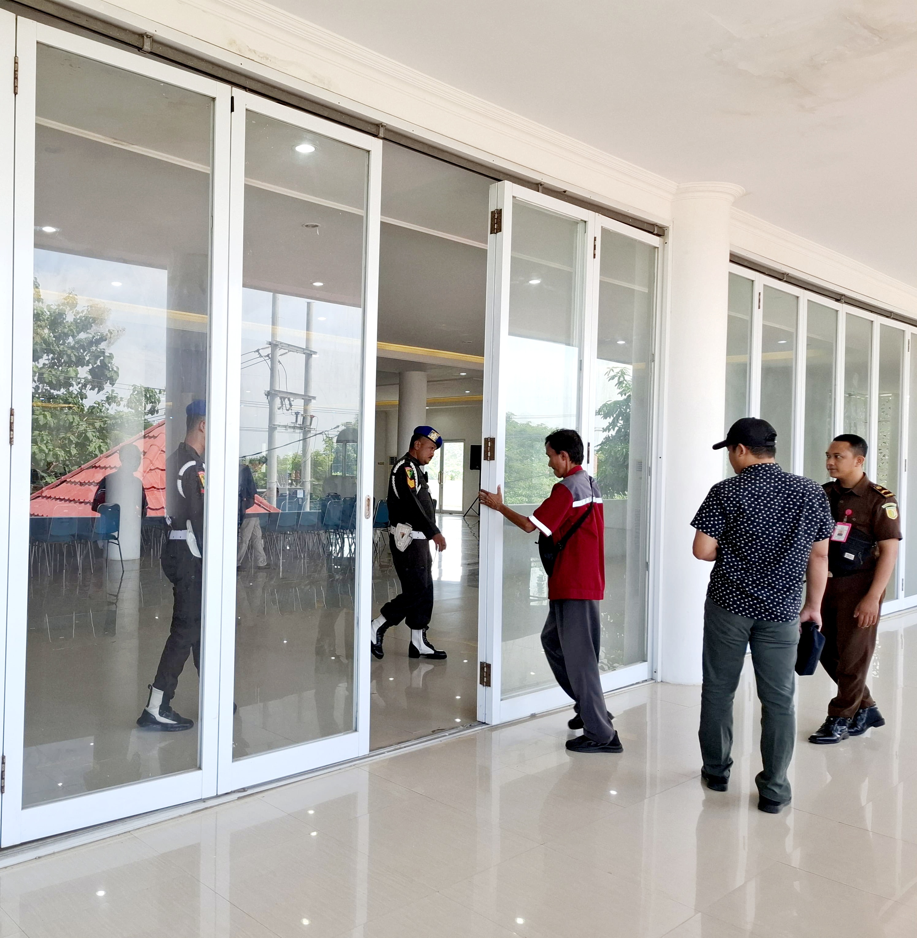 DIJAGA KETAT: Petugas Kejari Sumenep berjaga di pintu masuk tempat pemeriksaan Kades oleh Kejati Jatim terkait program BSPS di Gedung Islamic Center, Batuan, Rabu (21/5). (MOH. IQBAL/JPRM)