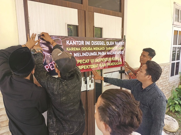KECEWA: Aktivis memasang gambar di kantor Inspektorat Pamekasan Rabu (4/6). (MOH. AZMI UNTUK JPRM)