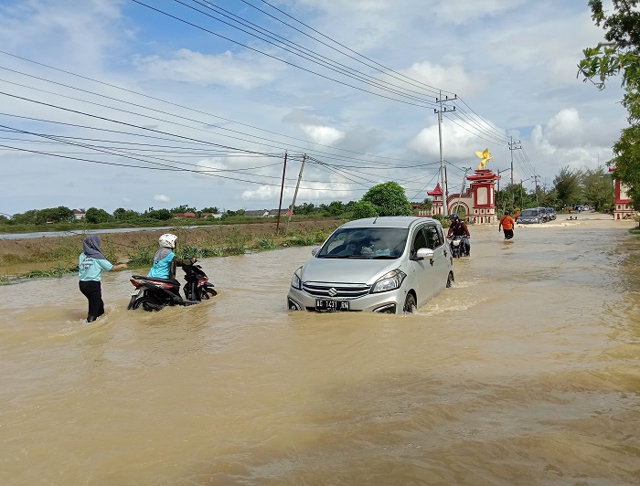 BUTUH PENANGANAN: Masyarakat melintas di Jalan Nasional Sumenep&ndash;Pamekasan yang terendam banjir, Rabu (14/5).