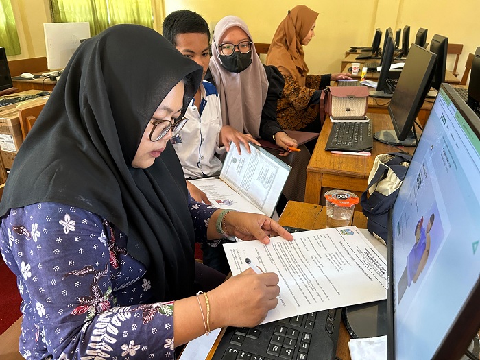 BERTUGAS: Operator SPMB SMAN 2 Bangkalan Laili Arofiyati melayani pengambilan PIN Kamis (12/6). (VIVIN AGUSTIN HARTONO/JPRM)