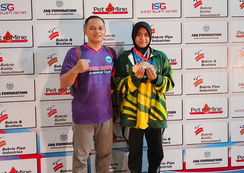 MEMBANGGAKAN: Perenang Sumenep Ajeng Ayu Syarifah bersama pelatih menunjukkan medali yang diperolehnya dari Kejurnas di Jakarta pada Minggu (1/6).