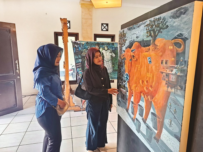 ESTETIK: Pengunjung menikmati lukisan yang dipajang dalam pameran bertajuk Berdua Kita Utuh di Hotel Suramadu, Sumenep, Jumat (13/6). (MOH. LATIF/JPRM)