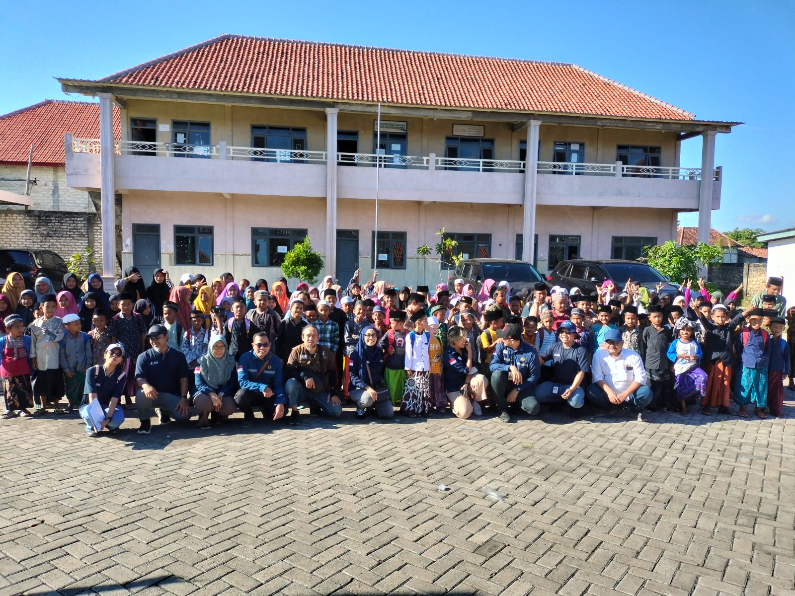 PAVINGISASI: Perwakilan Dirjen Migas, SKK Migas dan HCML berpose bersama santri di halaman lembaga pendidikan Zahrotut Tullab Desa Banjar Talela, Camplong, Sampang pada Selasa (3/6).