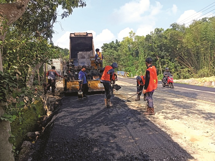 PELAN-PELAN: Pekerja sedang mengaspal pelebaran jalan di sekitar perbaikan Jembatan Pengeleyan di Kecamatan Tanah Merah, Bangkalan, Rabu (28/5). (TAUFIQ UNTUK JPRM)