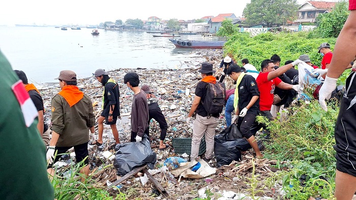 SEMANGAT: Mahasiswa dan mahasiswi UTM saat melakukan kerja bakti di kawasan pesisir Pelabuhan Timur Kamal, Bangkalan, Minggu (22/6).