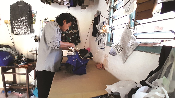 USAHA MANDIRI: Syafiudin, pelaku IKM di Kelurahan Kemayoran, Bangkalan, menyetrika baju milik pelanggannya, Kamis (19/6). (M. KHOLIL RAMLI/JPRM)