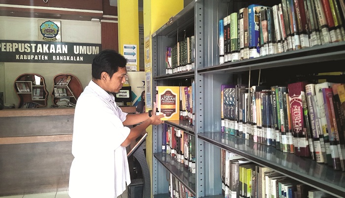 JENDELA DUNIA: Petugas Perpusda Bangkalan sedang merapikan koleksi buku Rabu (25/6). (M. KHOLIL RAMLI/JPRM)