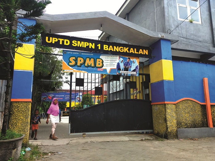 LENGANG: Warga dan seorang bocah keluar dari pintu masuk SMPN 1 Bangkalan yang terletak di Jalan Letnan Ramli Nomor 1B Bangkalan Kamis (26/6). (VIVIN AGUSTIN HARTONO/JPRM)