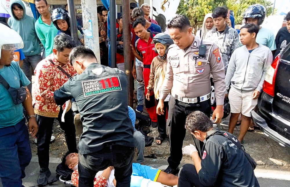 HATI-HATI: Anggota Satlantas Polres Pamekasan mengevakuasi korban laka lantas di Jalan Jokotole, Selasa (18/3).