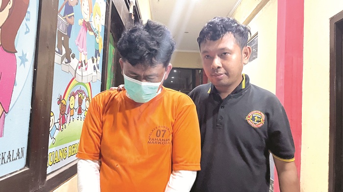 TERTUNDUK MALU: Tersangka kasus penyalahgunaan narkoba MR saat digiring polisi ke salah satu ruangan yang ada di Mapolres Bangkalan Kamis (10/7). (ZEINAL ABIDIN/JPRM)