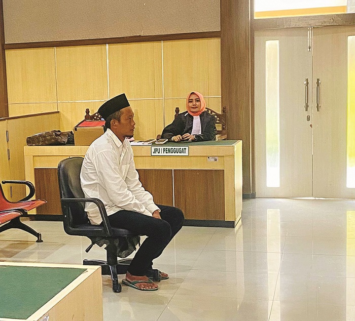KEMEJA PUTIH: Muarip duduk di bangku terdakwa Pengadilan Negeri Pamekasan Rabu (16/7). (MOH. IQBAL AFGANI/JPRM)