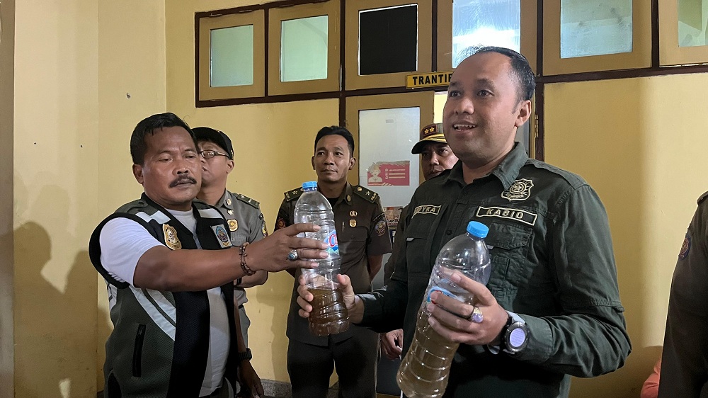 OPLOSAN: Sekretaris Satpol PP bangkalan Mohammad Hasbullah memperlihatkan minuman beralkohol (minol) oplosan, Kamis (10/7).