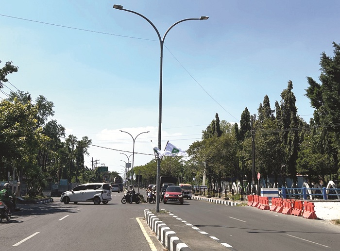 FASILITAS UMUM: Warga berkendara di dekat tiang lampu PJU yang terpasang di Jalan Soekarno-Hatta, Desa Bilaporah, Kecamatan Socah, Senin (21/7). (VIVIN AGUSTIN HARTONO/JPRM)