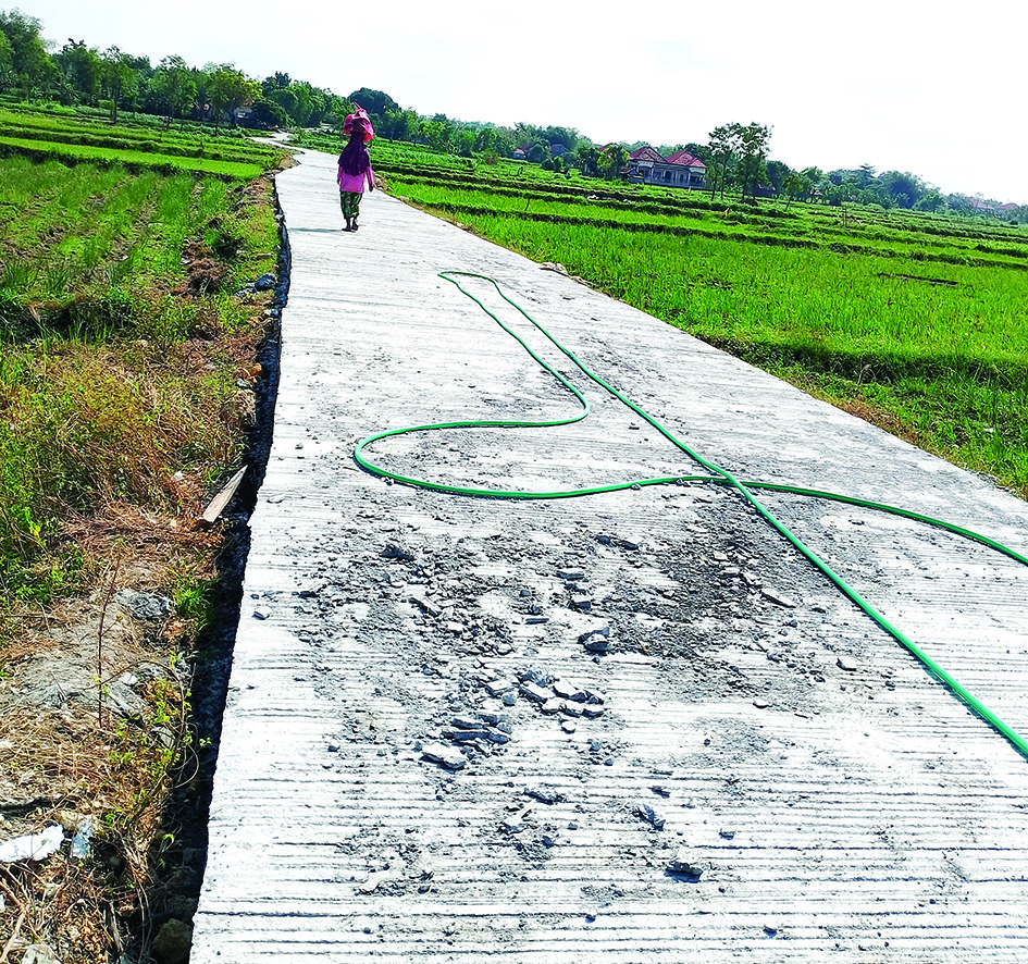 JANGGAL: Warga sedang berjalan di jalan rabat beton yang terletak di Desa Taddan, Kecamatan Camplong, Sampang, Rabu (16/7). (UBAIDILLAHIR RAIE/JPRM)