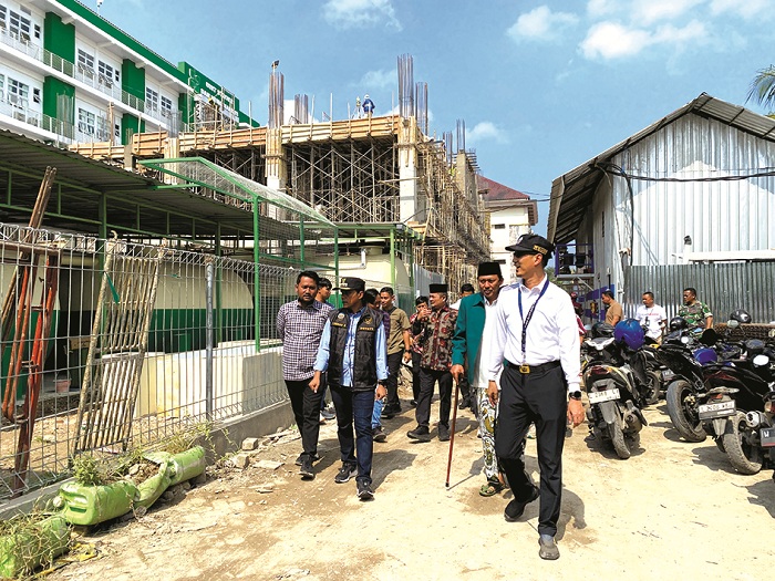 TURUN KE LAPANGAN: Bupati Bangkalan Lukman Hakim (pakai rompi) dan wakilnya, Moch. Fauzan Ja&rsquo;far, (batik) berada di dekat proyek pembangunan gedung lima lantai RSUD Syamrabu Jumat (25/7). (JUPRI/JPRM)