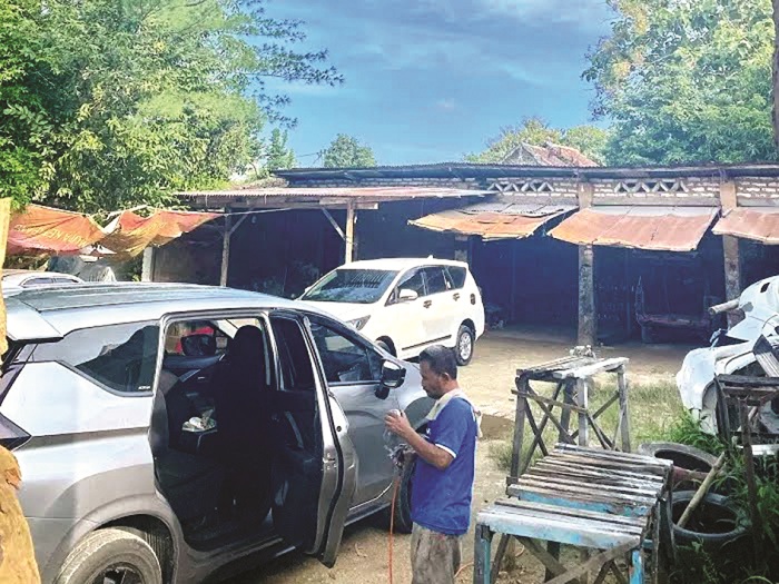 PERBAIKAN: Seorang pekerja memperbaiki mobil di bengkel Ismail, tempat raibnya mobil Suzuki Ertiga di Desa Kebunan, Kecamatan Kota Sumenep, Selasa (20/5). (JECKY SUSANTO UNTUK JPRM)