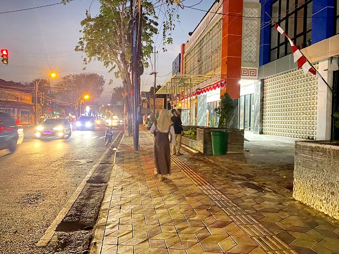 TUNTAS: Masyarakat saat melintas di saluran drainase yang baru tuntas diperbaiki di Jalan Jokotole Pamekasan Kamis (14/8). (AYU LATIFAH/JPRM)