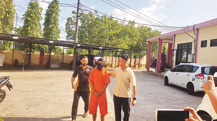 TAK BERKUTIK: Tersangka Asmad digiring aparat kepolisian di Mapolres Bangkalan Jumat (15/8). (ZEINAL ABIDIN/JPRM)