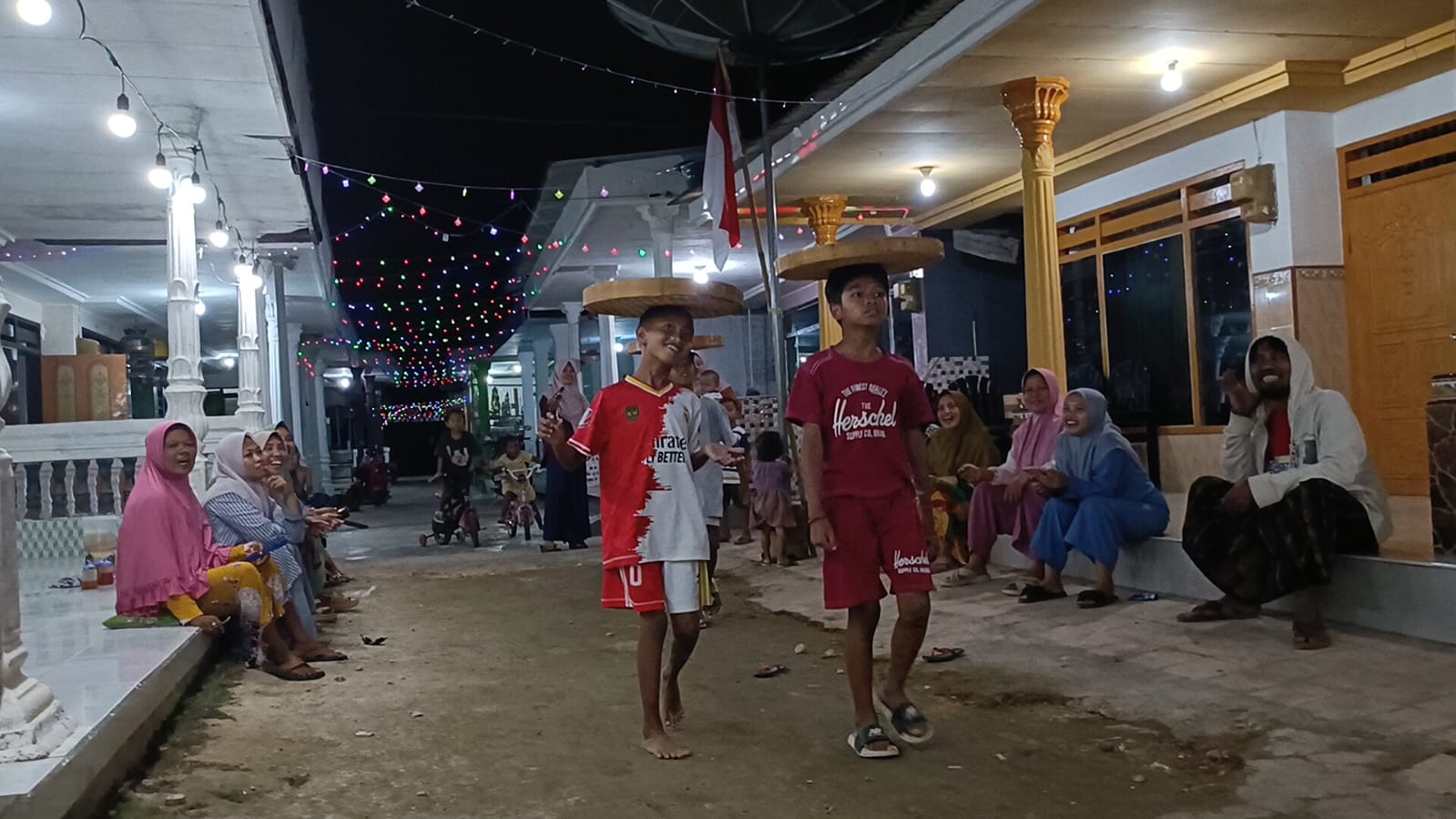 TANGKAS: Warga menonton Syukron Mubarok El Hakim (kiri), Dirga (kanan), dan Raka (belakang) yang mengikuti lomba nyunggi tampah di Kampung Pocang Timur, Cangkreng, Kecamatan Lenteng, Rabu (13/8) malam