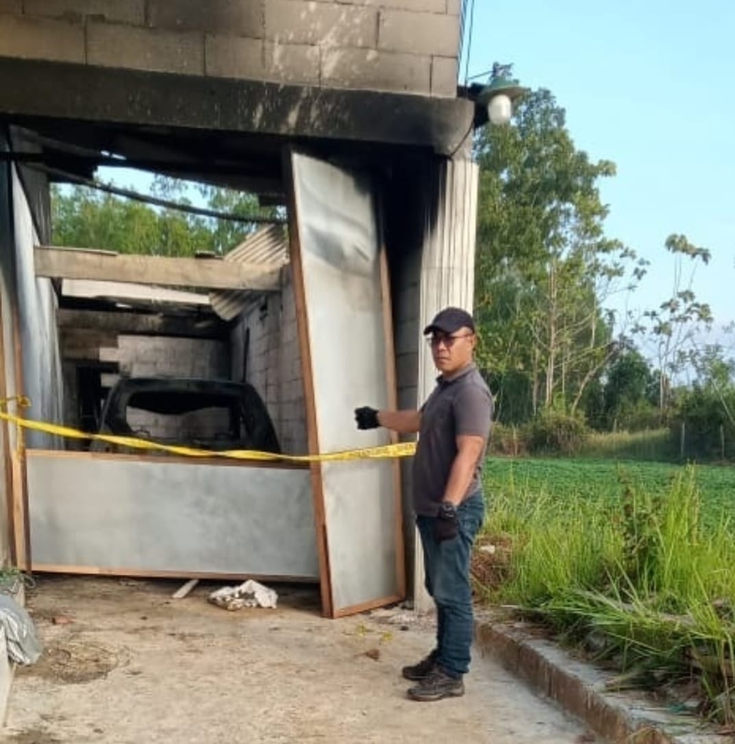 HANGUS: Anggota Polres Sampang berada di TKP pembakaran oleh OTK di Desa Bajrasokah, Kecamatan Kedungdung, Sampang, Minggu (17/8).