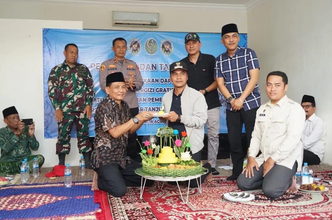 SEREMONIAL: Bupati Bangkalan Lukman Hakim menyerahkan potongan nasi tumpeng usai meresmikan SPPG JK Resto di Desa Bumi Anyar, Kecamatan Tanjung Bumi, Senin (18/8).
