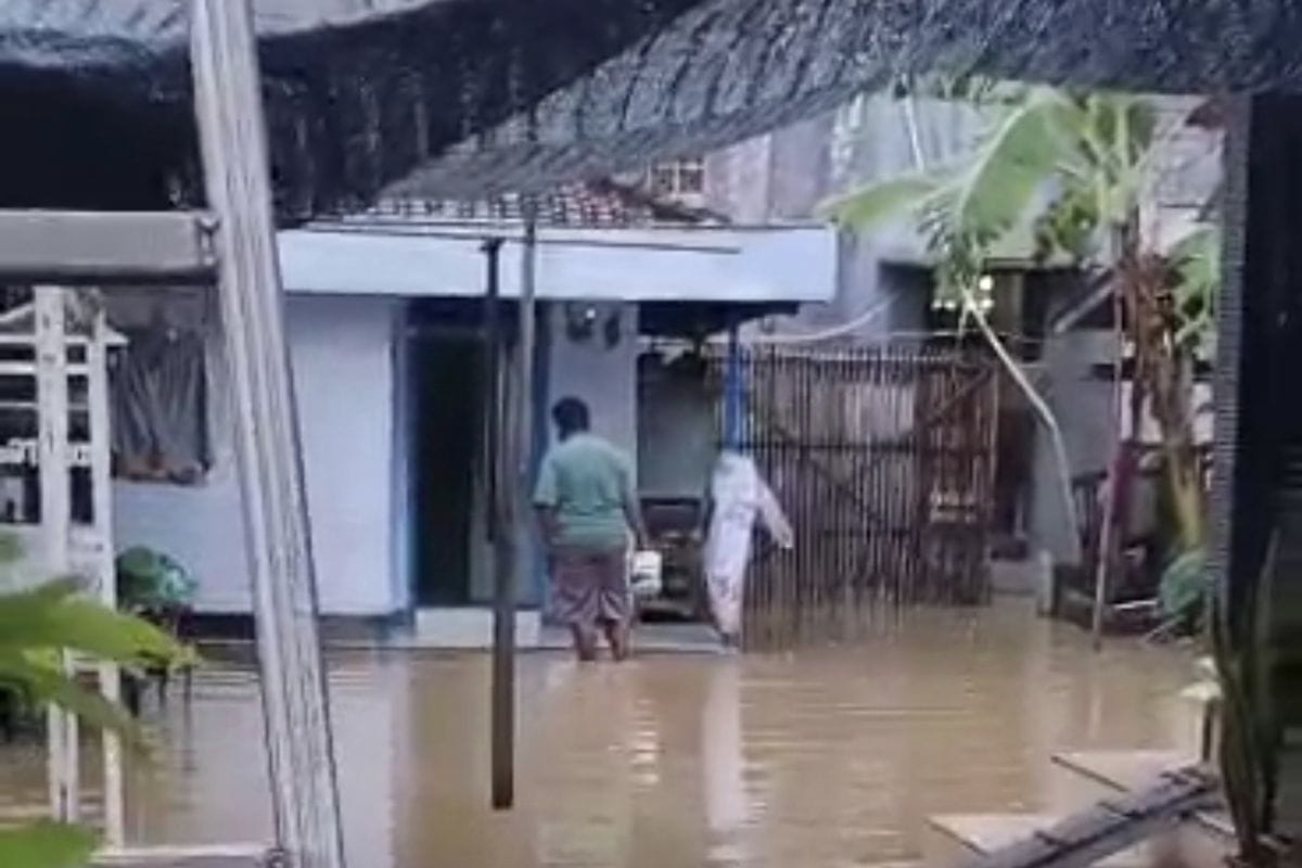 MENGGENANG: Warga di Arosbaya berada di halaman rumahnya yang sedang digenangi banjir akibat hujan, Rabu (20/8).