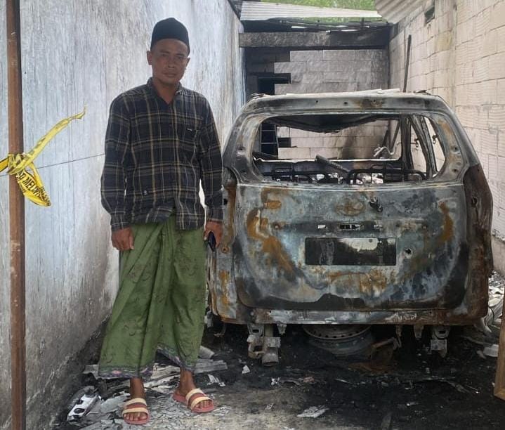 MINTA KEADILAN: Abd Manan berada di dekat mobilnya yang dibakar OTK di garasi rumahnya di Desa Bajrasokah, Kecamatan Kedungdung, Sampang, Senin (18/8).
