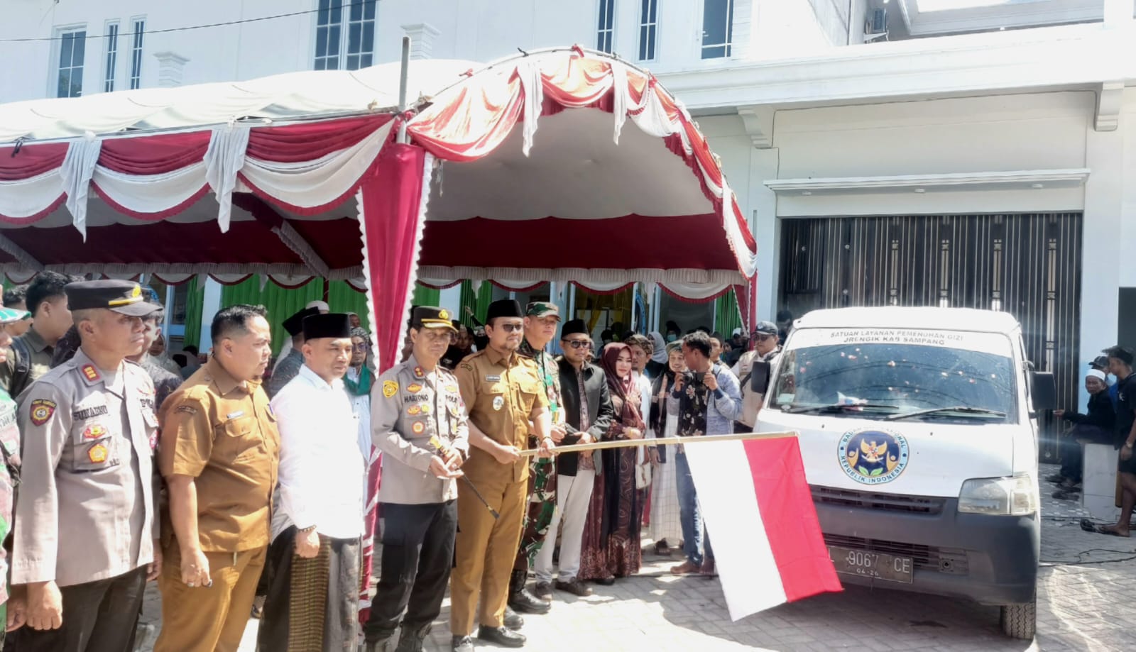 SIMBOLIS: Wabup Sampang Ahmad Mahfudz (pegang bendera) melepas keberangkatan armada SPPG Darun Najah di Desa Jungkarang, Kecamatan Jrengik, Sampang, Senin (25/8).