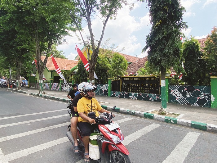 PENDIDIKAN: Pengendara sepeda motor melintas di depan SDN Bugih 3 yang terletak di Jalan Kabupaten Pamekasan, Minggu (24/8). (AYU LATIFAH/JPRM)