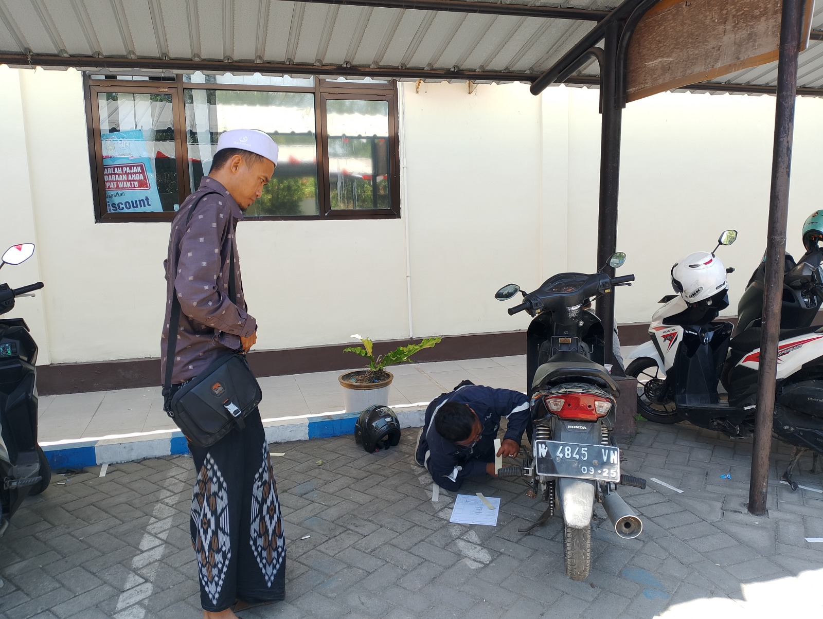 BERTUGAS: Karyawan Samsat Sampang melakukan cek noka motor milik warga di halaman kantor samsat, Kamis (4/9).
