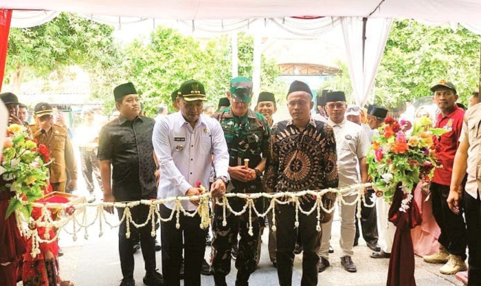 SIMBOLIS: Bupati Sampang Slamet Junaidi menggunting untaian melati sebagai penanda peluncuran SPPG Yayasan Kemas Desa Kotah, Kecamatan Jrengik, Sampang, Selasa (9/9). (JUNAIDI PONDIYANTO/JPRM)