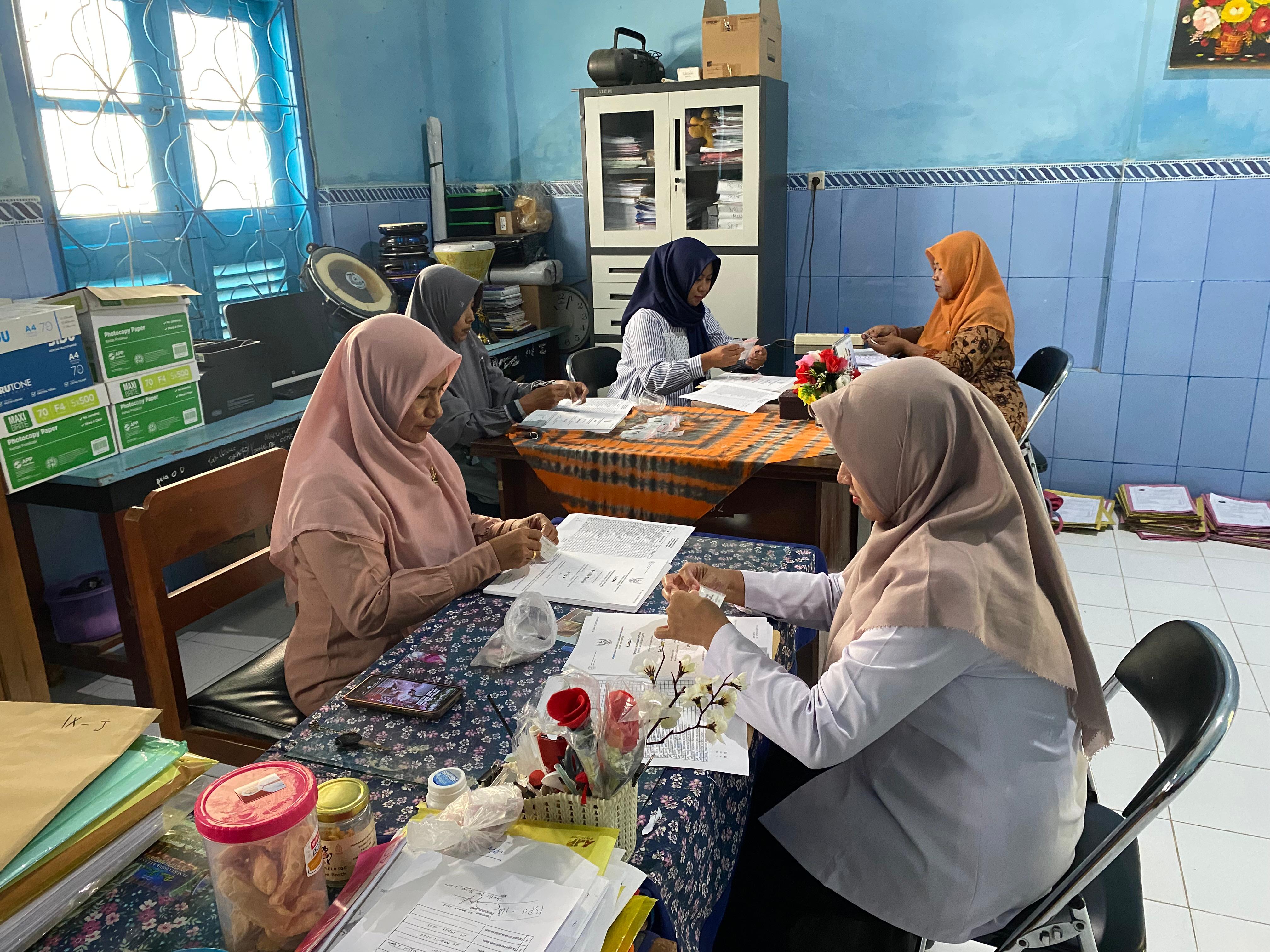PENGABDIAN: Guru SMPN 1 Pamekasan saat mengisi rapor murid pada Senin (7/7).