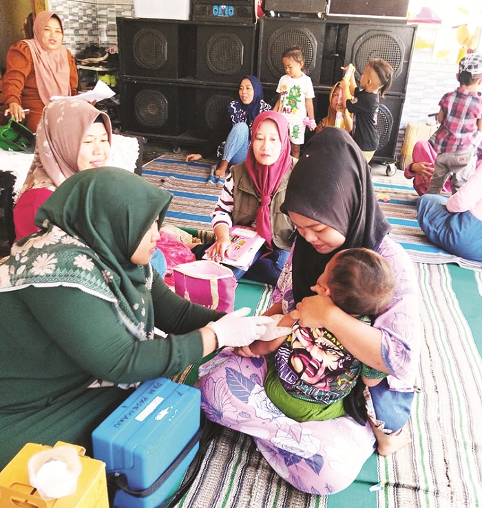 TURUN LAPANG: Petugas saat memberikan imunisasi campak di Puskesmas Pademawu pada Minggu (14/9). (DINKES UNTUK JPRM)